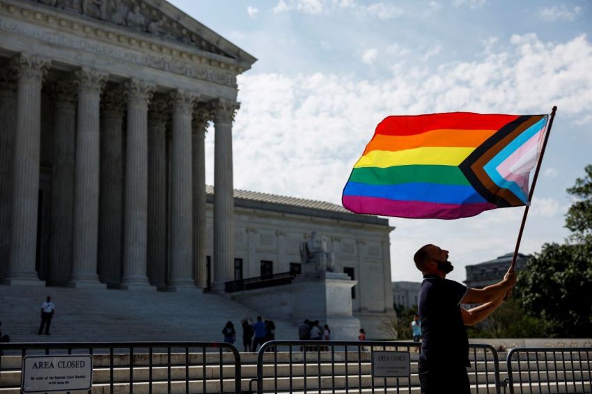 Same-sex marriage supporter Vin Testa, of Washington, DC, waves a LGBTQIA pride flag in front of the U.S. Supreme Court Building as he makes pictures with his friend Donte Gonzalez to celebrate the anniversary of the United States v. Windsor and the Obergefell v. Hodges decisions on June 26, 2023, in Washington, DC.