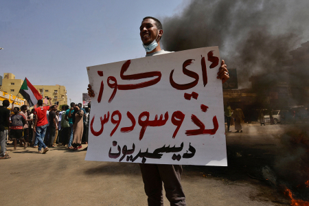 A Sudanese demonstrator holds a placard during a protest in the city of Khartoum Bahri, the northern twin city of the capital, to demand the government's transition to civilian rule, on Oct. 21, 2021. The placard reads in Arabic