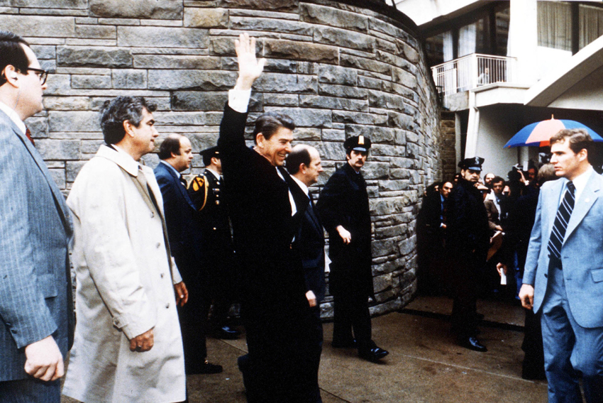 President Ronald Reagan waves to onlookers moments before an assassination attempt by John Hinckley Jr. on March 30, 1981, by the Washington Hilton in Washington, D.C. James Brady is visible third from the left.