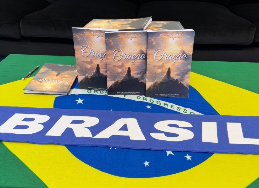Copies of the Brazilian Portuguese edition of The Prayer: Rise with Jesus — 30 Days to Transform Your Life by Stefania Leão & Alexander Debelov sit on a Brazilian flag.
