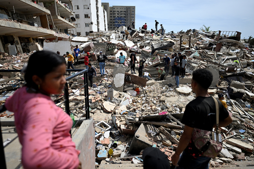Residents search for victims through the rubble of a collapsed building in Catia La Mar, La Guaira state, about 30 km northwest of Caracas, on June 25, 2026, following an earthquake. A twin earthquake that was Venezuela's largest in over a century has killed at least 188 people and destroyed multiple buildings near the capital, where residents searched on June 25 for missing relatives.