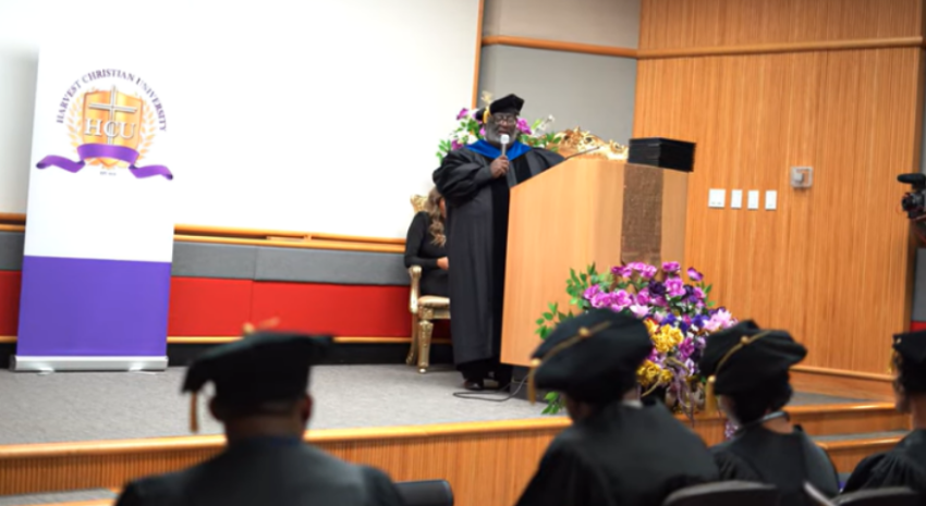 A screenshot of Carl Robinson II of Harvest Christian University speaking at a graduation ceremony in Dallas, Texas.