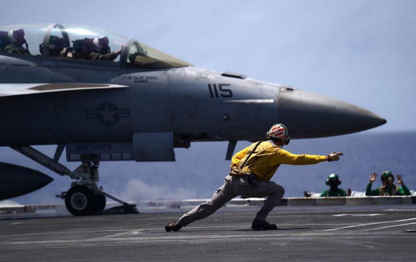A US Navy aviation boatswain's mate directs a F/A-18F Super Hornet assigned to Strike Force Squadron (VFA) 154 on the flight deck aboard the aircraft carrier USS Theodore Roosevelt (CVN-71) while the ship is moored in Honolulu, Hawaii, during Exercise RIMPAC (Rim of the Pacific) 2026 on July 17, 2026. 
