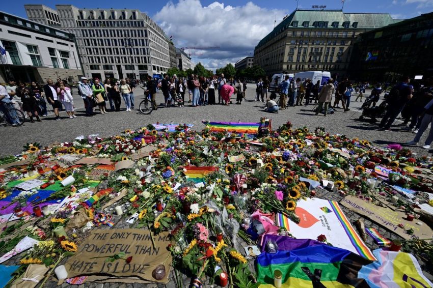 Tributes, like flowers, condolence placards, candles and rainbow flags, have been arranged on the ground on Pariser Platz in front of landmark Brandenburg Gate in Berlin, on July 27, 2026, two days after a car ramming attack that killed one person and injured 29 near the Christopher Street Day (CSD) parade.