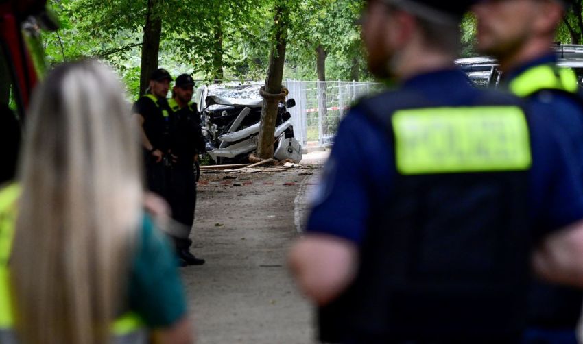 Police work near the wreckage of a car on July 26, 2026, in the Tiergarten park in Berlin, Germany, where a car was driven the evening before into people, killing one person and injuring 16, on the outskirts of the Christopher Street Day (CSD) parade.