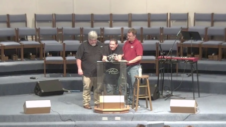 Pastor Matt Olson is physically upheld at the point of his exhaustion while preaching the sufficiency of Christ's righteousness from the book of Romans on June 2, 2026.