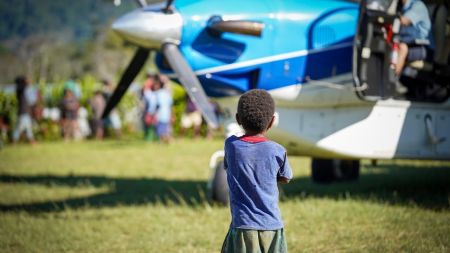A child stands in front of a JAARS plane.