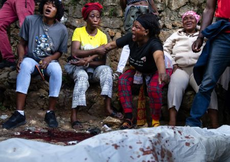 A body lies on the ground as people react following overnight violence in which more than dozens were killed by armed gangs in Kenscoff, a neighborhood near Port-au-Prince, Haiti, on August 24, 2026. Gang members attacked displaced people huddling inside a church near Haiti's capital, killing around 40, some of them execution-style, the mayor told AFP on Monday. 