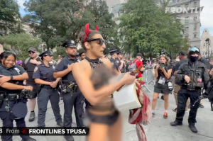 Scantily-clad trans activist wielding crucifix rips out pages of the Bible at 9/11 protest