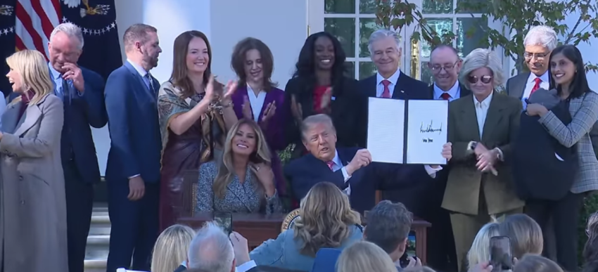 President Donald Trump signs an executive order in the White House Rose Garden alongside first lady Melania Trump and several Cabinet members, Oct. 19, 2026.