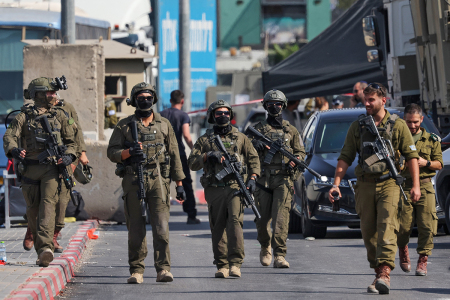 Israeli soldiers gather at the scene of an earlier fire exchange between armed Palestinians and Israeli forces following an incident at the norther checkpoint of Hebron in the Israeli-occupied West Bank on Oct. 23, 2026. Israeli troops on October 23 shot dead two suspected Palestinian assailants in the West Bank after a shooting that left at least five people wounded, officials said.