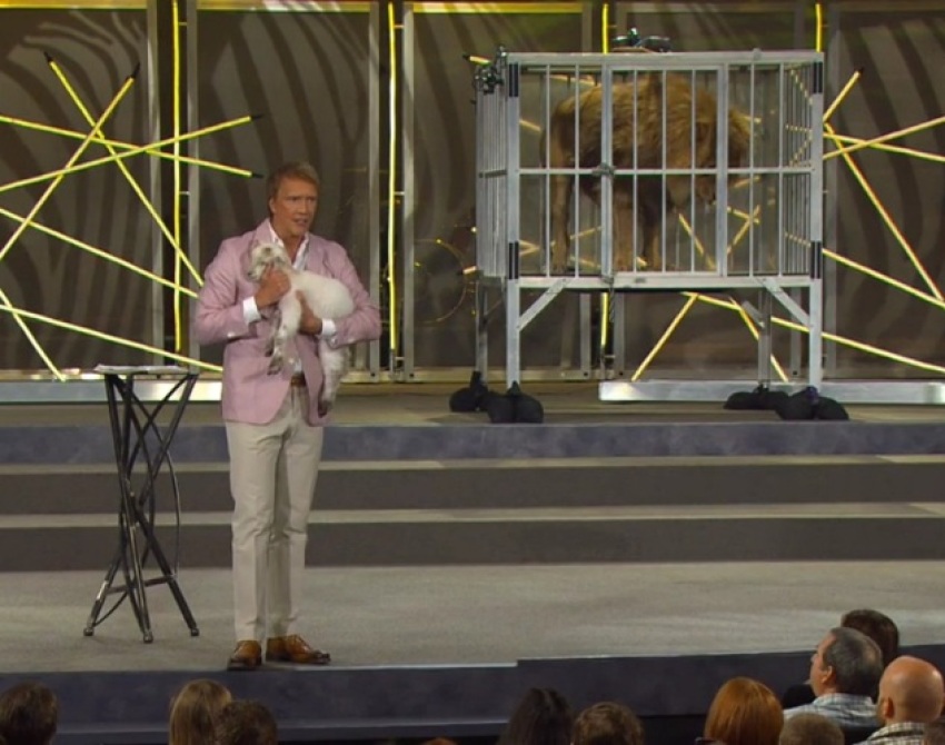 Pastor Ed Young of Fellowship Church in Grapevine, Texas, holds a lamb near a cage with a live lion during his Easter "Wild" sermon on April 8, 2012.