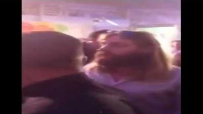 Nathan Grindal being shown led away by six security guards at a darts event in England, after the crowd disrupted a game by chanting "Jesus" at him.