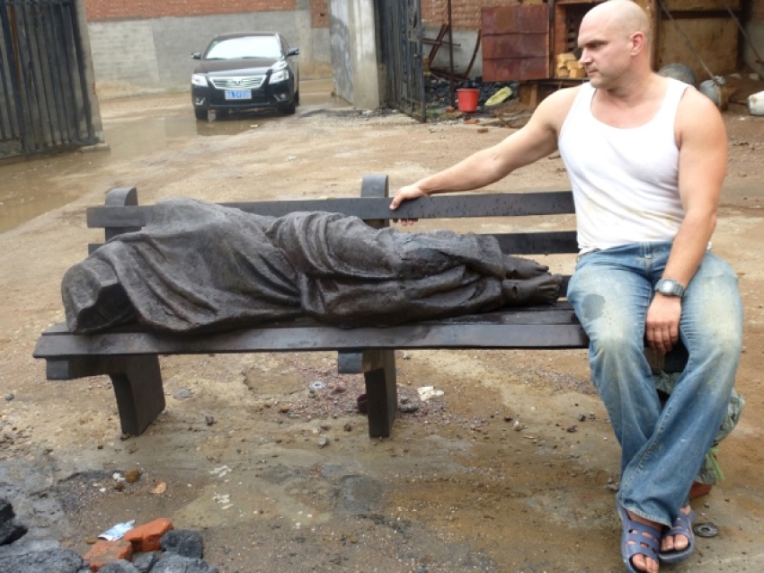 Canadian sculptor Timothy Schmalz sitting next to his sculpture 