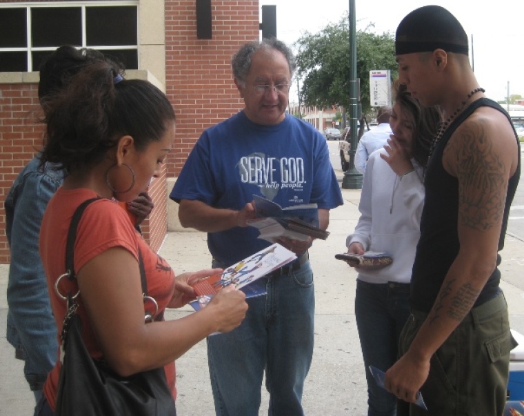 Lakewood Church street evangelism team leader Marcel Aguilar reads from "30 Thoughts for Victorious Living" by Joel Osteen before praying for the family outside a Harris County jail in downtown Houston, Texas, on Sept. 21, 2013.