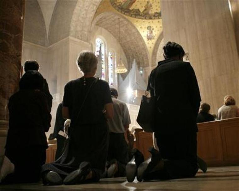 Catholics kneel during Mass