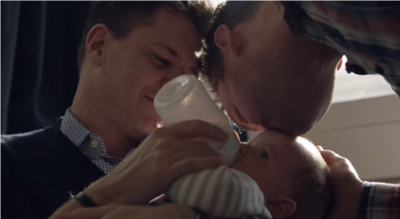 Two gay men pose with a baby in Honey Maid's