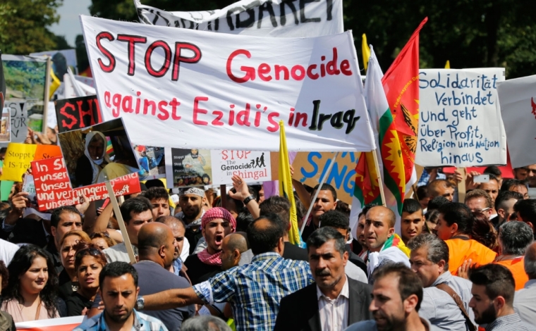 Kurds of the ethnic minority of Yazidis hold up a banner reading "Stop genocide against Yazidis in Iraq" as they march through the streets of Bielefeld August 9, 2014. Some 10,000 ethnic Kurds of the Yazidis sect, who practice an ancient faith related to Zoroastrianism, protested in the western German city on Saturday against Islamic State (IS) militants, who are surging across northern Iraq near the Kurdistan borders in their drive to eradicate unbelievers such as Christians and Yazidis.