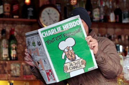 A man poses with the new issue of French satirical weekly Charlie Hebdo entitled "Tout est pardonne" ("All is forgiven"), which shows a caricature of Muslim prophet Muhammad, at a cafe in Nice, southern France, January 14, 2015.