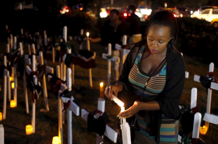 A woman lights a candle on a wooden cross during a memorial vigil for the people killed by gunmen at the Garissa University College, at the