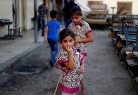 A displaced Iraqi girl, who fled from the violence in Mosul, stands at a school in Baghdad, September 1, 2014.