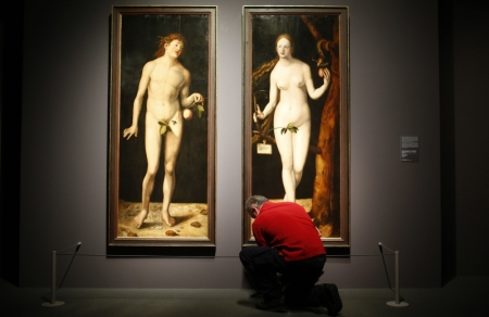 A museum worker cleans the floor in front of true to scale copies of the paintings