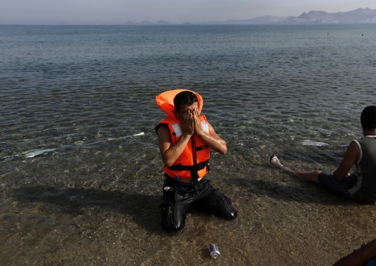 An Iranian migrant prays moments after arriving with another six family members by paddling an engineless dinghy from the Turkish coastat a beach on the Greek island of Kos August 15, 2015. United Nations refugee agency called on Greece to take control of the "total chaos" on Mediterranean islands, where thousands of migrants have landed. About 124,000 have arrived this year by sea, many via Turkey, according to Vincent Cochetel, UNHCR director for Europe.