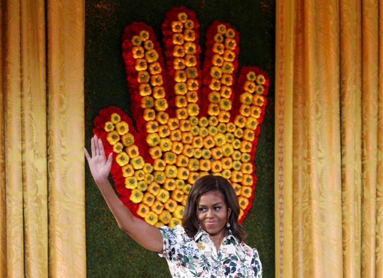 Standing before a "hand" made of peppers, U.S. first lady Michelle Obama waves while hosting the 2015 winners of the "Healthy Lunchtime Challenge" a nationwide recipe challenge for kids that promotes cooking and healthy eating, for the annual Kids’ State Dinner at the White House in Washington, July 10, 2015.