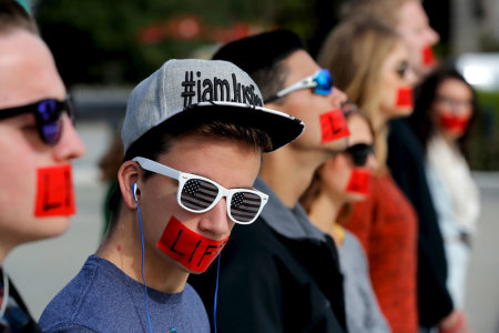 Members of the anti-abortion protest group Bound 4 Life wear red tape over their mouths reading