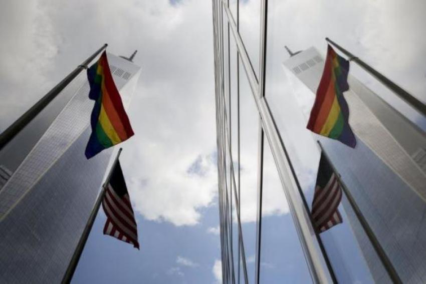 A gay pride flag flies alongside the U.S. flag (lower), as they are reflected off the front of 200 West Street, also known as the Goldman Sachs Tower, in lower Manhattan, New York June 26, 2015.