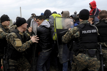 Macedonian policemen push back Syrian, Iraqi and Afghan refugees who try to force their way through the Greek-Macedonian borders near the village of Idomeni, Greece, November 22, 2015.