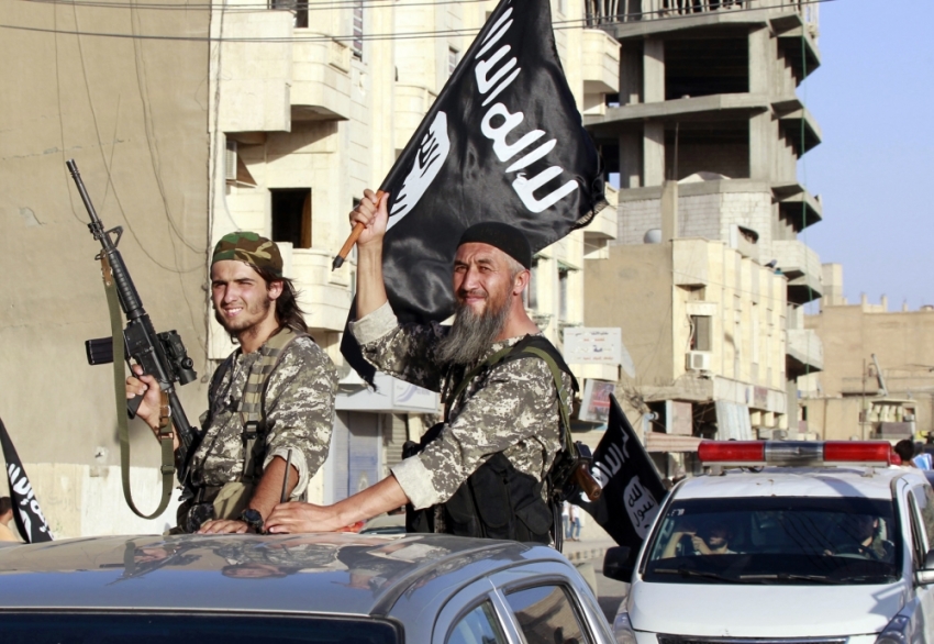 Militant Islamist fighters wave flags as they take part in a military parade along the streets of Syria's northern Raqqa province June 30, 2014. The fighters held the parade to celebrate their declaration of an Islamic 