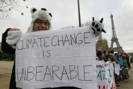A man wears a polar bear costume and holds a banner with the message, "Climage Change is Unbearable" as he participates in a demonstration near the Eiffel Tower in Paris, France, as the World Climate Change Conference 2015 (COP21) continues near the French capital in Le Bourget, December 12, 2015.