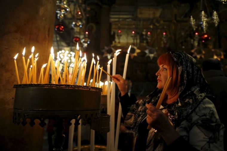 A worshipper lights candles as she attends a Christmas service according to the Eastern Orthodox calendar, in the church of Nativity in the West Bank city of Bethlehem, January 6, 2016.