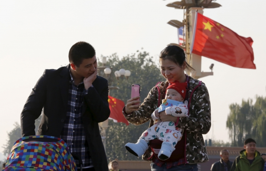 A couple takes pictures with their baby on the Tiananmen Gate in Beijing, China, November 2, 2015.