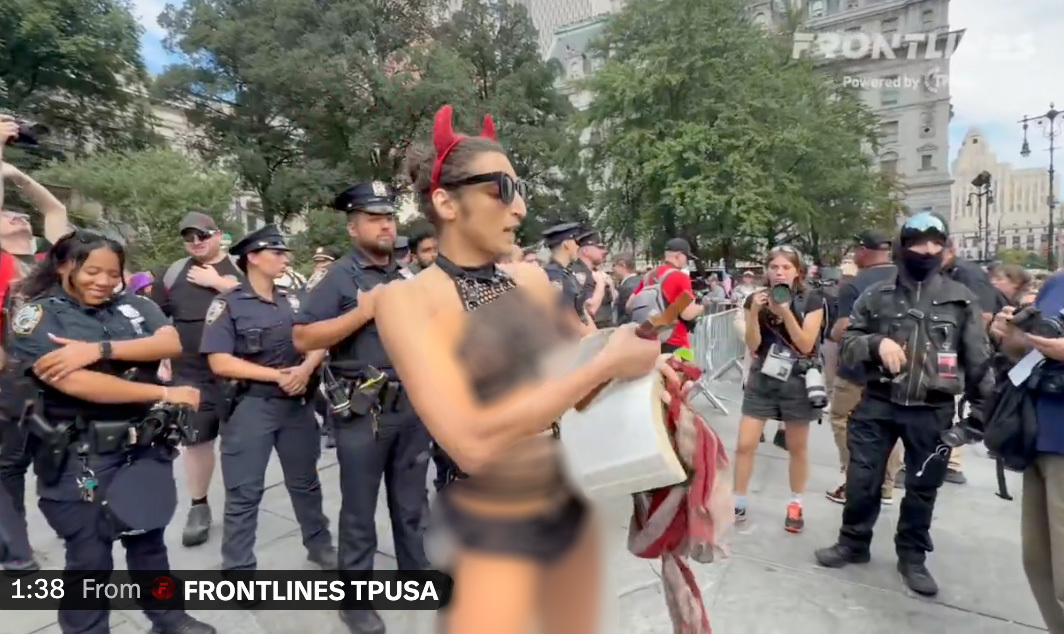 Scantily-clad trans activist wielding crucifix rips out pages of the Bible at 9/11 protest