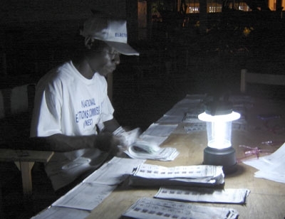 A Liberian election worker counts ballots by lantern light. (Photo: UMNS / Mary Miller)