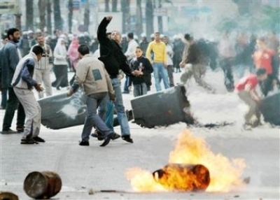 Egyptian muslim protesters throw rocks past a burning gas canister near the St. Maximus Church in the northern Mediterranean city of Alexandria in Egypt Sunday, April 16, 2006. Police fired live ammunition into the air and lobbed tear gas into rioting cro