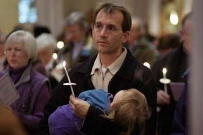 A man holding his son in his arms joins in an Ecumenical Prayer Service for the kidnapped Christian Peacemakers at St. Michael's Cathedral in Toronto, Ontario December 18, 2005. The four members of the Christian Peacemakers were kidnapped in Iraq on Novem