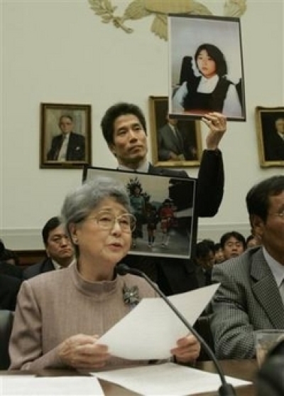 Sakie Yokota, mother of Japanese kidnap victim Megumi Yokota, testifies on Capitol Hill, Thursday, April 27, 2006 before a House committee. Holding up photos of her daughter is her son Takuya Yokota. (Photo: AP / Pablo Martinez Monsivais)