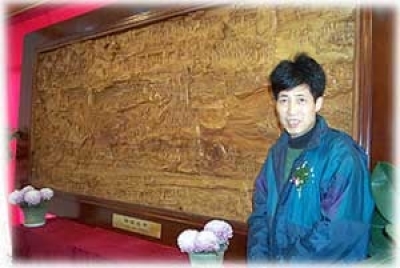 Zhang Wan Long standing alongside the woodcarving depicting the