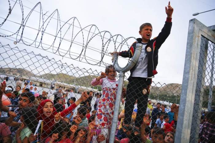Refugee youths gesture from behind a fence as German Chancellor Angela Merkel, Turkish Prime Minister Ahmet Davutoglu, EU Council President Donald Tusk and European Commission Vice-President Frans Timmermans (all not pictured) arrive at Nizip refugee camp near Gaziantep, Turkey, April 23, 2016.