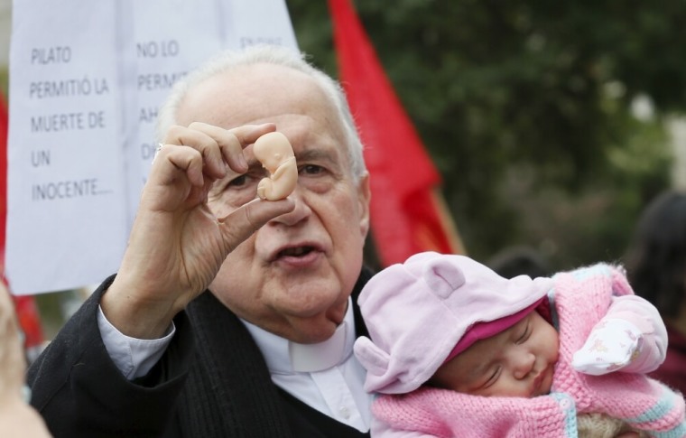 Archbishop Gonzalo Duarte prays as he holds a fetus figurine and a baby outside Congress during a rally against the draft law of the Chilean government which seeks to legalize abortion, in Valparaiso, August 4, 2015.