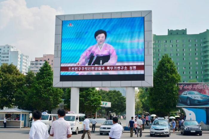 North Koreans walk past near a huge screen broadcasting the government's announcement on North Korea's fifth nuclear test in Pyongyang, North Korea, in this photo released by Kyodo on September 9, 2016.