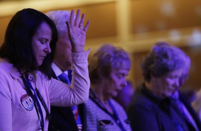 Attendees bow their heads in prayer at the morning plenary session of the Values Voter Summit in Washington September 26, 2014.
