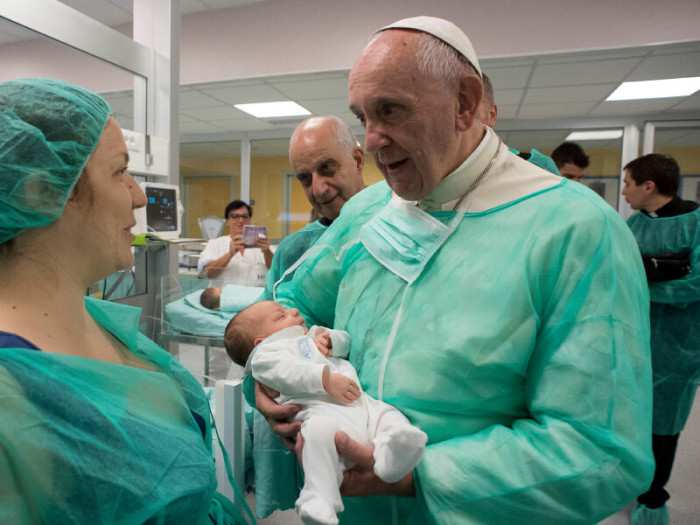 Pope Francis holds an infant at the neonatal unit as he visits the San Giovanni hospital in Rome, September 16, 2016.