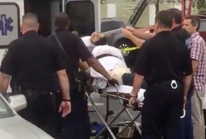 A policeman takes a photo of a man they identified as Ahmad Khan Rahami, who is wanted for questioning in connection with an explosion in New York City, as he is placed into an ambulance in Linden, New Jersey, in this still image taken from video September 19, 2016.