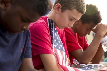 Tempie Williams (L), 12, Dallin Cogbill, 13, and Kade Harkness, 13, bow their heads in prayer during a vigil for Marine Lance Cpl. Squire K. "Skip" Wells, one of the five military servicemen slain last week in Chattanooga in a domestic terror attack, at Sprayberry High School in Marietta, Georgia July 21, 2015. Wells, 21, a reservist, was the youngest victim of an attack being investigated as an act of domestic terrorism. He was killed last Thursday when authorities say Mohammod Youssuf Abdulazeez opened fire at a Naval Reserve Center in Chattanooga, Tenn., slaying Wells and three other Marines. A sailor later died of his wounds.