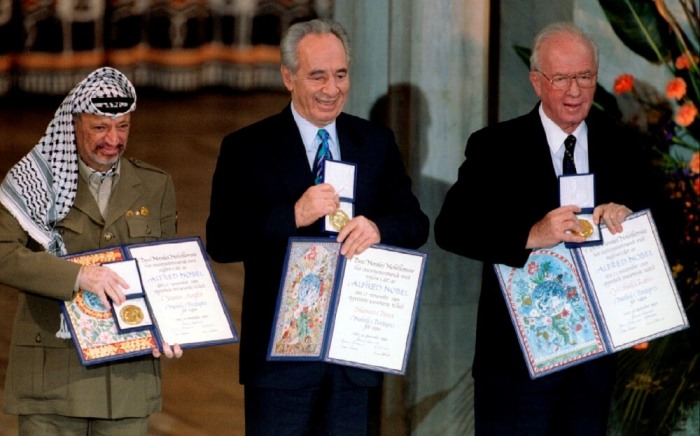 PLO Chairman Yasser Arafat, Israeli Foreign Minister Shimon Peres and Israeli Prime Minister Yitzhak Rabin (from L to R) show their shared Nobel Peace Prize awards to the audience in the Oslo City Hall in Oslo in this December 10, 1994, file photo.