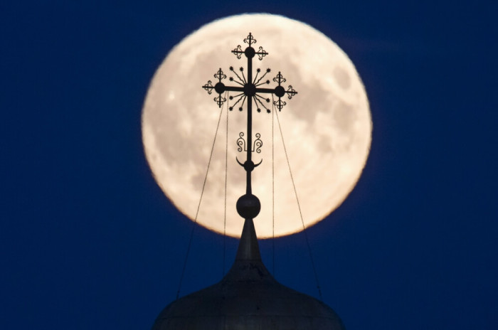 A cross atop of a local monastery is seen silhouetted against the moon in the settlement of Poschupovo in Ryazan region, Russia, September 27, 2015. Sky-watchers around the world are in for a treat Sunday night and Monday when the shadow of Earth casts a reddish glow on the moon, the result of rare combination of an eclipse with the closest full moon of the year. The total 'supermoon' lunar eclipse, also known as a 'blood moon' is one that appears bigger and brighter than usual as it reaches the point in its orbit that is closest to Earth.
